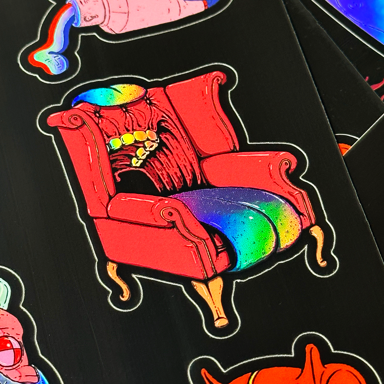 Holographic sticker of a red armchair with a rainbow-colored, toothy mouth on the seat.